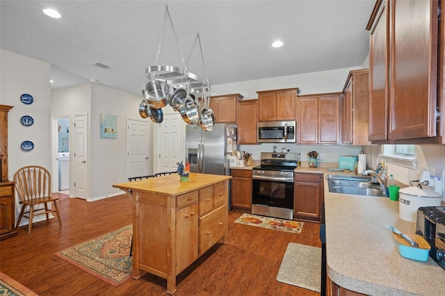 kitchen with dark hardwood / wood-style flooring, sink, stainless steel appliances, and a kitchen island