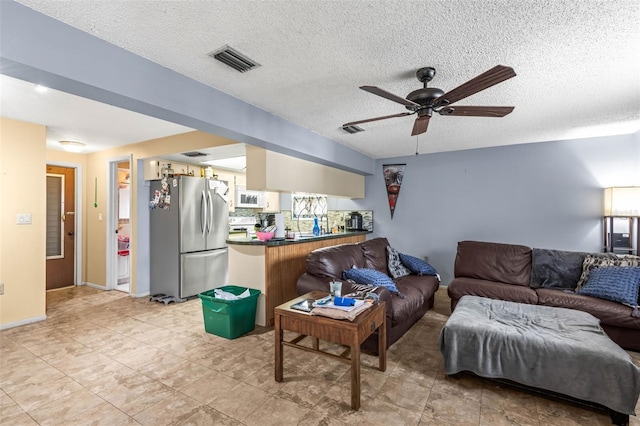 living room featuring a textured ceiling and ceiling fan