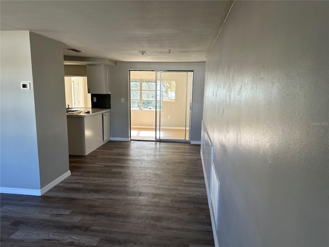 interior space featuring dark wood-type flooring, white cabinets, and backsplash