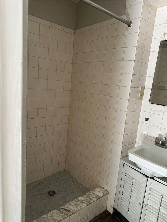 bathroom with vanity, a tile shower, and tile walls