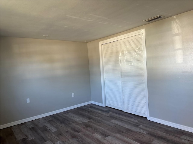 unfurnished bedroom with dark hardwood / wood-style floors and a closet