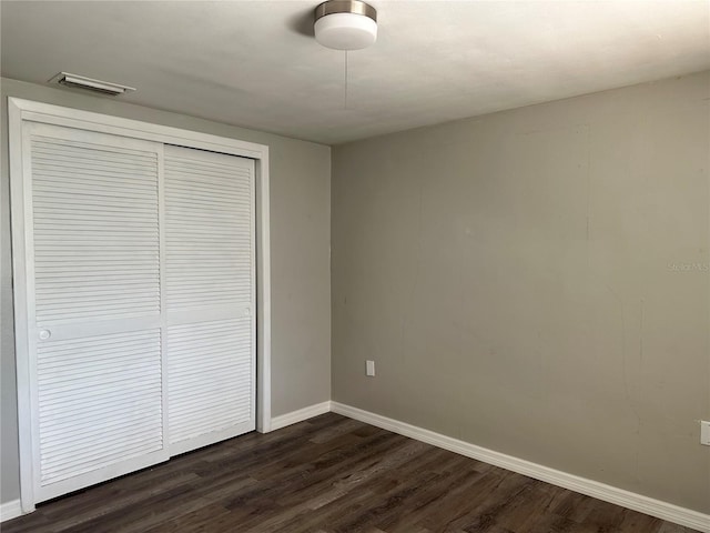 unfurnished bedroom featuring dark wood-type flooring and a closet