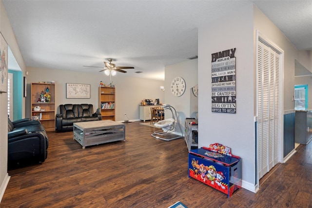 living room featuring dark wood-type flooring, a textured ceiling, and ceiling fan