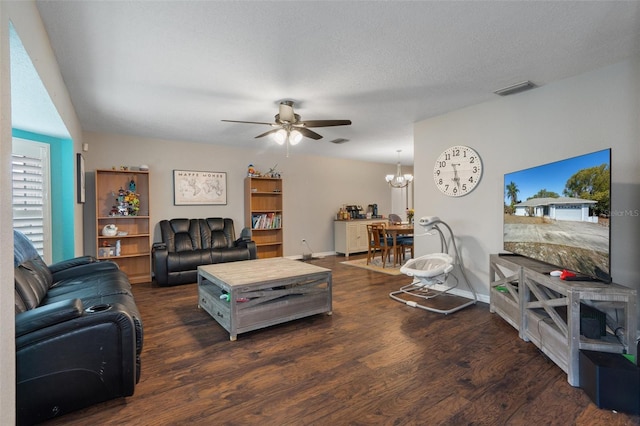 living room featuring dark wood-type flooring, ceiling fan with notable chandelier, and a textured ceiling