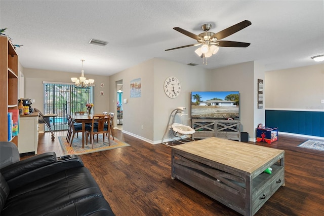 living room with ceiling fan with notable chandelier, dark wood-type flooring, and a textured ceiling