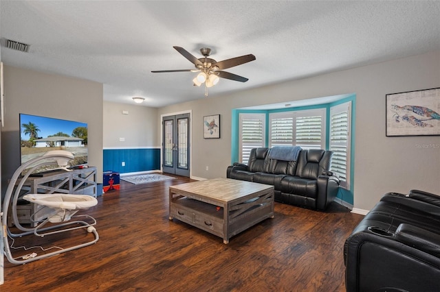 living room with ceiling fan, dark wood-type flooring, and a textured ceiling