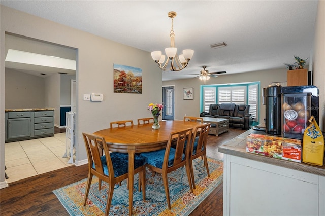 dining room with ceiling fan with notable chandelier and light hardwood / wood-style floors