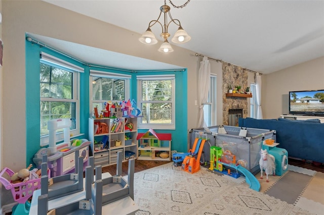 playroom featuring lofted ceiling, a fireplace, plenty of natural light, and light wood-type flooring