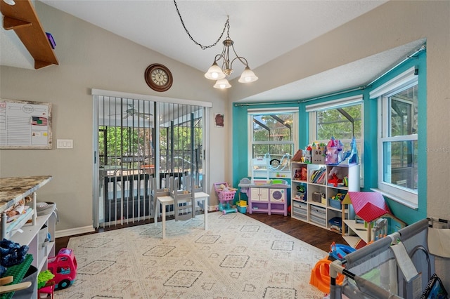 rec room featuring vaulted ceiling, plenty of natural light, dark wood-type flooring, and a chandelier