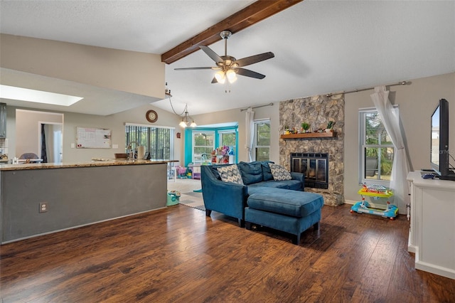 living room with dark hardwood / wood-style floors, vaulted ceiling with skylight, a fireplace, ceiling fan, and a textured ceiling