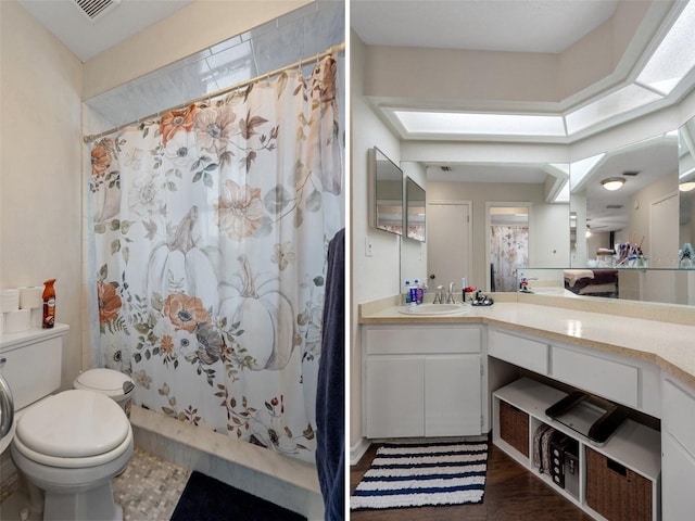 bathroom with walk in shower, toilet, a skylight, vanity, and hardwood / wood-style floors