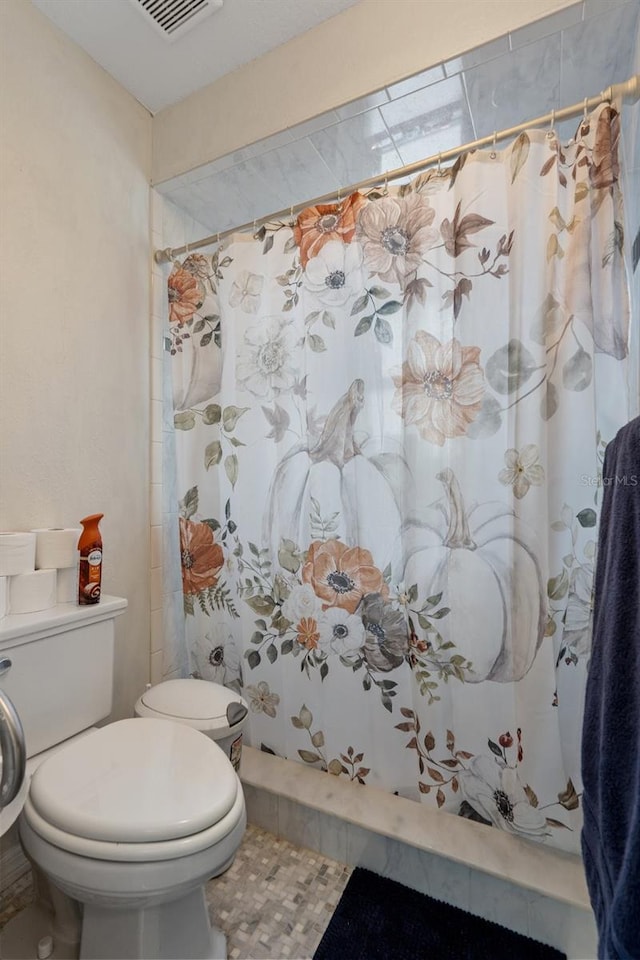 bathroom with toilet and a shower with shower curtain