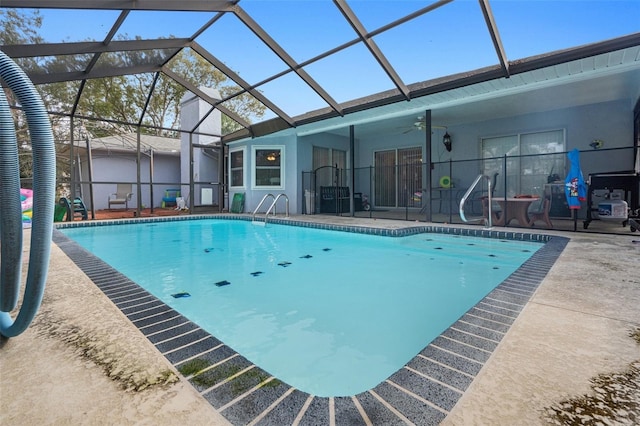 view of pool with a patio area, ceiling fan, and glass enclosure