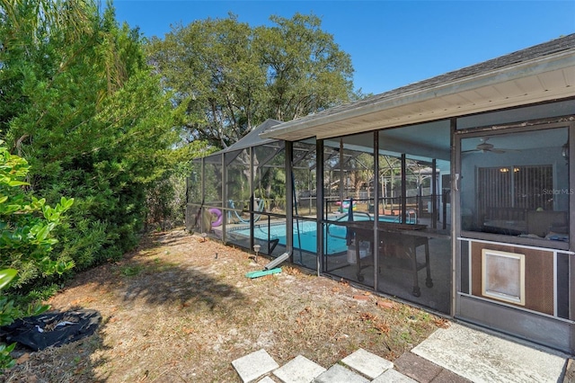 view of yard with ceiling fan and a lanai