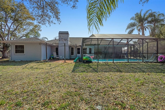 rear view of house featuring glass enclosure and a lawn