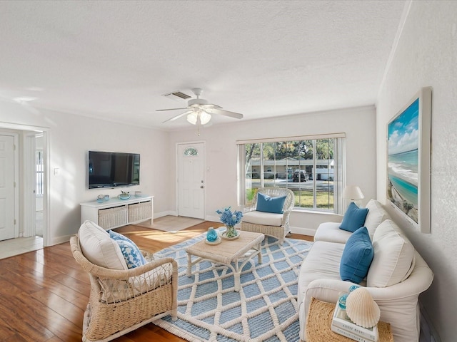 living room featuring wood-type flooring, ceiling fan, and a textured ceiling