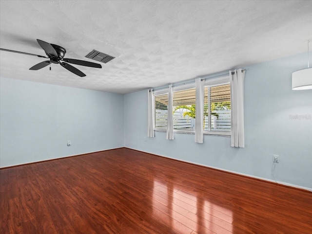 empty room featuring ceiling fan, a wall mounted AC, hardwood / wood-style floors, and a textured ceiling