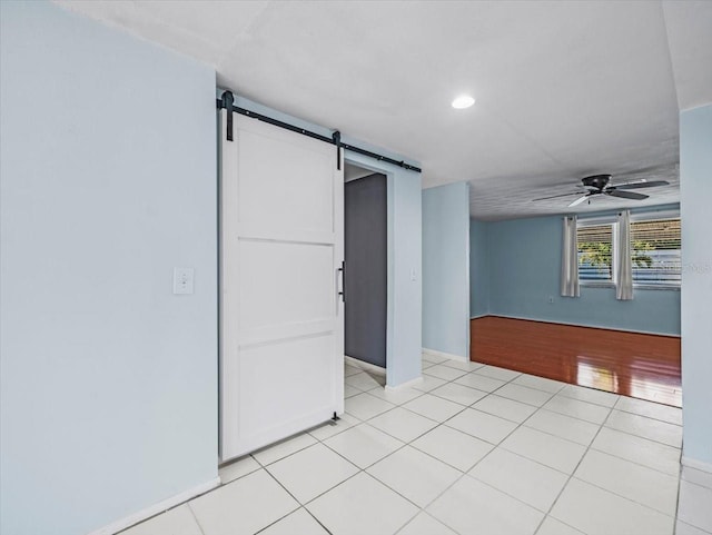 tiled spare room with ceiling fan and a barn door