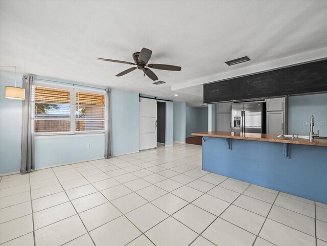 kitchen featuring sink, a breakfast bar area, stainless steel fridge, kitchen peninsula, and a barn door