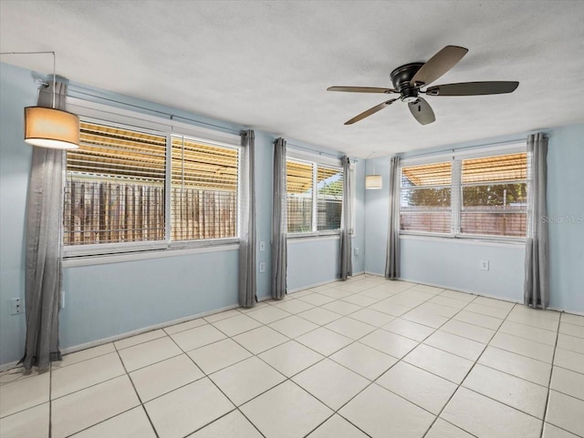 tiled empty room with ceiling fan and a textured ceiling