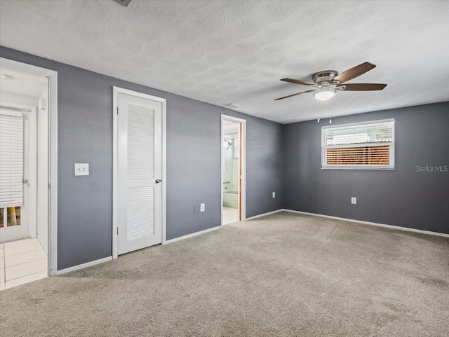 unfurnished bedroom featuring ceiling fan, ensuite bathroom, a textured ceiling, and carpet flooring