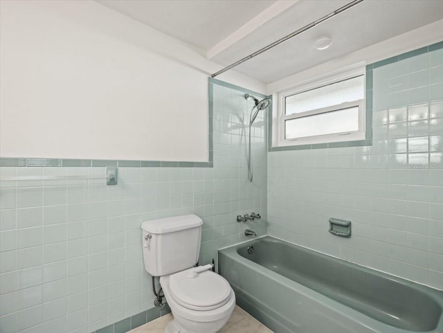 bathroom featuring tiled shower / bath, tile patterned floors, toilet, and tile walls