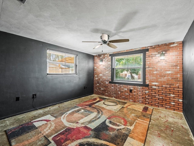 spare room featuring ceiling fan, brick wall, and a textured ceiling