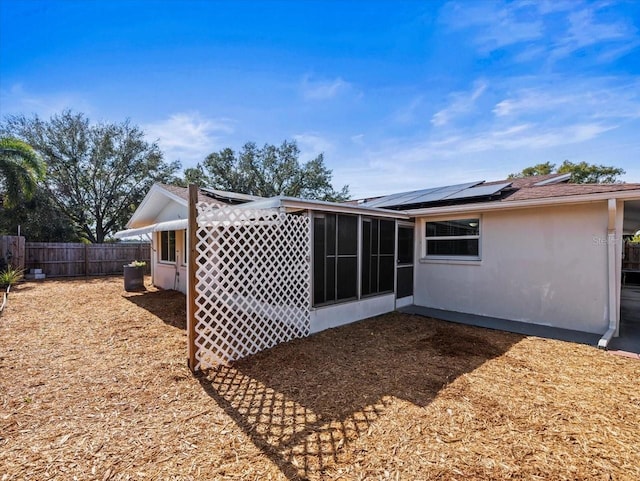 rear view of house with a sunroom and solar panels