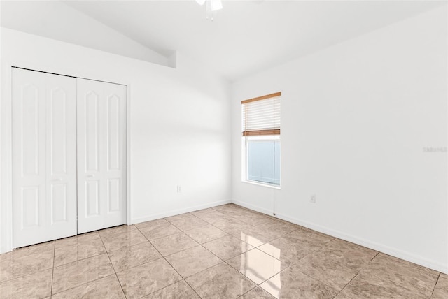 unfurnished bedroom featuring lofted ceiling, light tile patterned floors, ceiling fan, and a closet