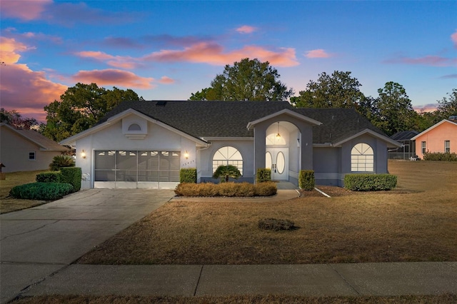 ranch-style house featuring a garage and a lawn