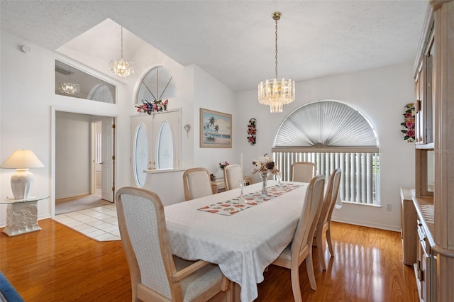 dining space featuring a textured ceiling, a notable chandelier, and light hardwood / wood-style floors