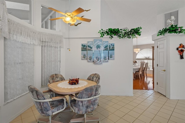 dining area with tile patterned flooring and ceiling fan with notable chandelier