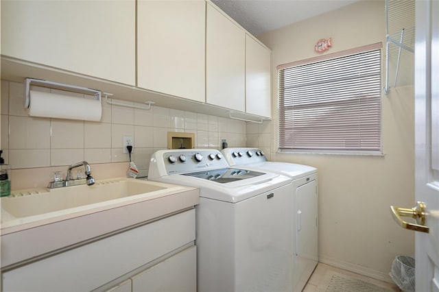 laundry area featuring cabinets, separate washer and dryer, and sink