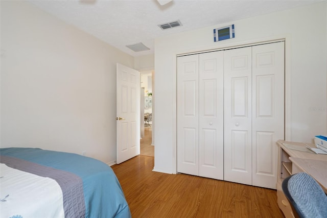 bedroom with hardwood / wood-style flooring, ceiling fan, a textured ceiling, and a closet