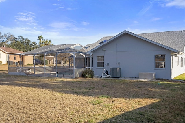 rear view of property featuring a yard, central air condition unit, and glass enclosure