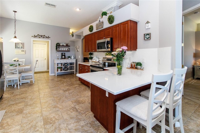 kitchen with pendant lighting, a breakfast bar area, kitchen peninsula, and appliances with stainless steel finishes