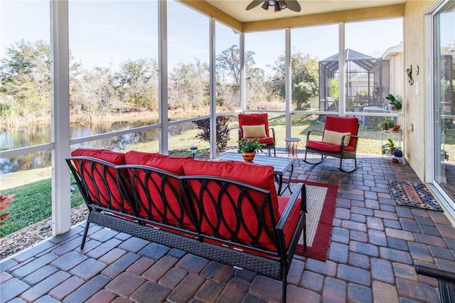 sunroom / solarium featuring ceiling fan and a water view