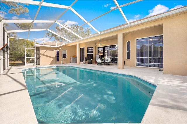 view of pool with ceiling fan, glass enclosure, and a patio area