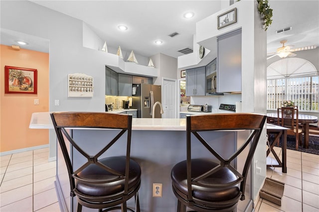 kitchen featuring sink, gray cabinetry, light tile patterned floors, kitchen peninsula, and stainless steel appliances