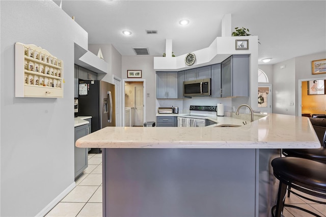 kitchen with sink, gray cabinetry, stainless steel appliances, light tile patterned flooring, and kitchen peninsula