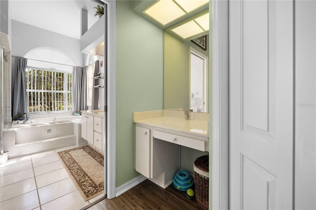 bathroom featuring tile patterned floors, vanity, and tiled bath