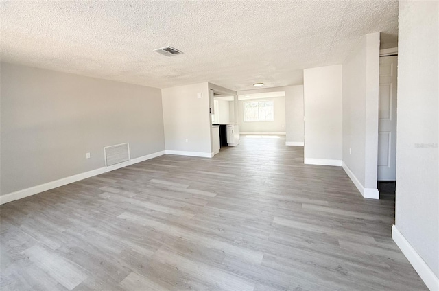 unfurnished living room featuring light hardwood / wood-style flooring and a textured ceiling