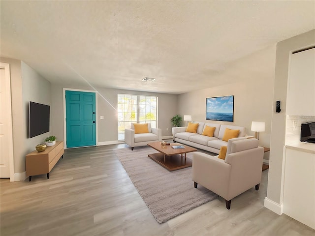 living room with light hardwood / wood-style floors and a textured ceiling