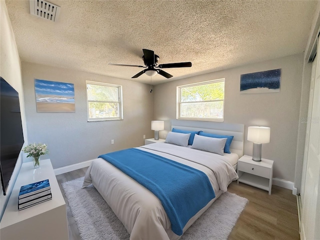 bedroom featuring ceiling fan, hardwood / wood-style flooring, and a textured ceiling