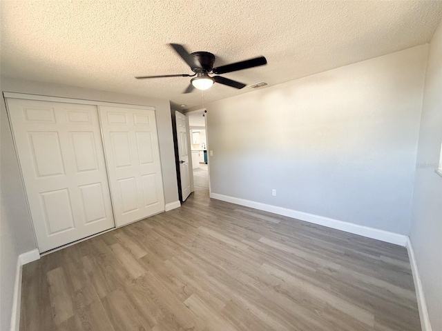 unfurnished bedroom featuring a closet, ceiling fan, a textured ceiling, and light hardwood / wood-style flooring