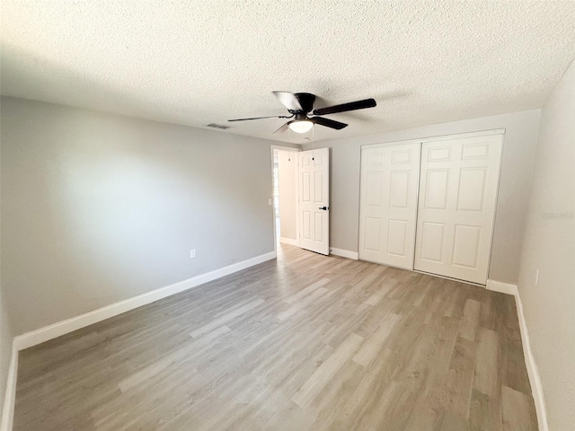 unfurnished bedroom featuring light hardwood / wood-style floors, a closet, and a textured ceiling