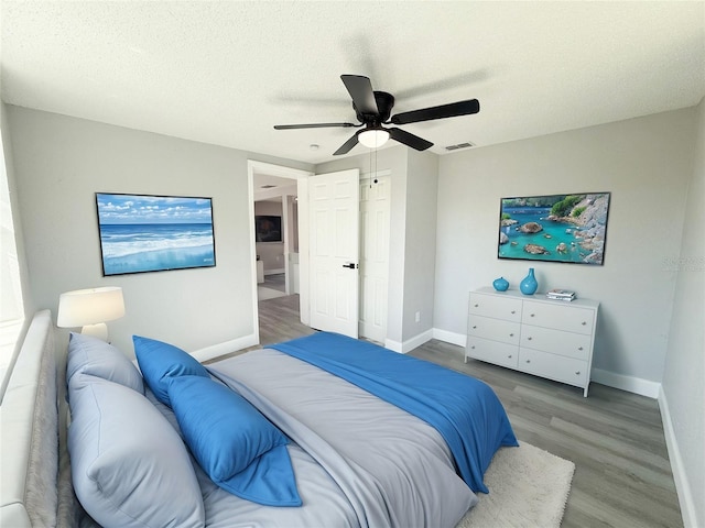 bedroom featuring ceiling fan, hardwood / wood-style floors, and a textured ceiling