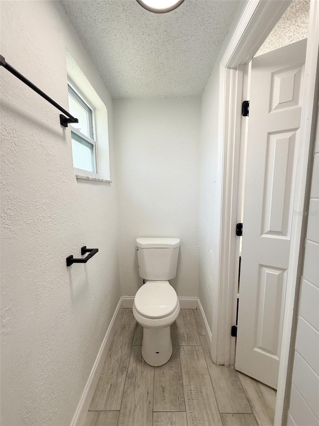 bathroom with hardwood / wood-style floors, a textured ceiling, and toilet