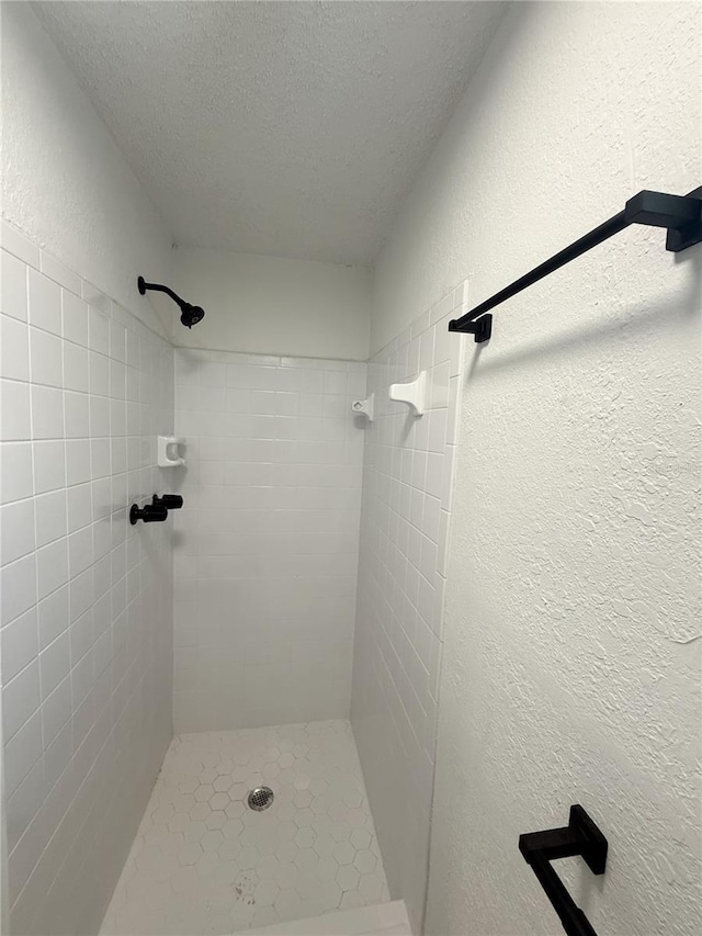 bathroom featuring a textured ceiling and a tile shower