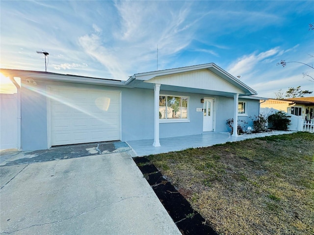 ranch-style home with a garage, a front lawn, and covered porch